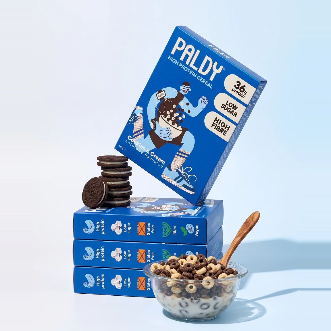 Paldy Cookies & Cream high protein cereal boxes stacked with cookies and a bowl of cereal